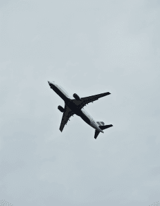 A commercial passenger jet aircraft in flight, with its nose and engines visible against a gray sky