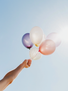 A person releasing balloons into the sky, each balloon labeled with a stressor