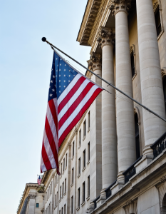 An American flag waving in front of a government building featuring ornate architecture