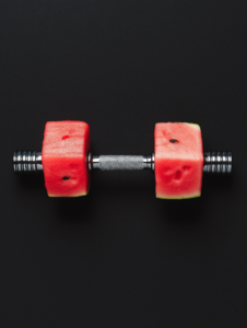 A barbell with watermelons as weights, symbolizing the light yet nourishing power of natural foods in enhancing fitness