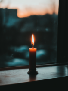 A candle flame gently flickering in a quiet room, symbolizing the light of faith guiding through darkness