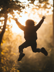 A child leaping into the air, framed by sunlight, symbolizing the carefree joy of childhood