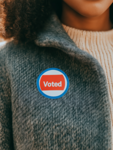 A close-up of a I Voted sticker on a person’s clothing, representing civic duty and pride in participation