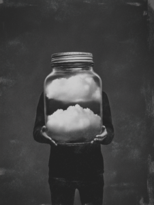 A figure holding a jar filled with clouds, symbolizing the containment of emotions like sadness, confusion, or hope