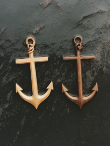 A pair of anchors dropping side by side into the same sea, representing stability and security provided by a close bond