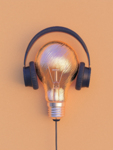 A pair of headphones plugged into a lightbulb, illustrating how consumer technology enhances creativity and innovation