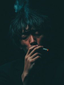 A person looking stressed while holding a cigarette, representing the link between smoking and stress relief