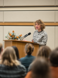 A person speaking at a podium about addiction awareness, emphasizing advocacy and education