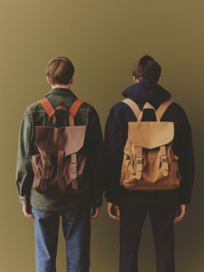 A shared backpack with two straps, each held by a different person, symbolizing the shared burdens and support in close relationships