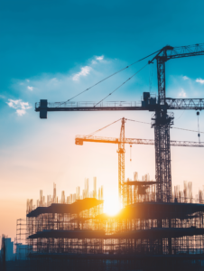 A silhouette of a construction site with cranes and scaffolding against the backdrop of a rising sun, symbolizing new beginnings and progress