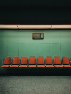 A subway train morphing into a row of chairs in a waiting area, representing the blending of waiting and travel