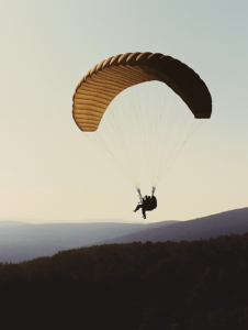 A tandem parachute with two people descending together, representing the trust and support needed in difficult or uncertain situations