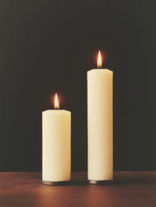 Two candles with flames merging into one, representing shared warmth, light, and energy between bonded individuals