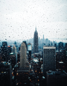 A cityscape viewed through a rain-streaked window, distorting and obscuring reality