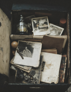 A dusty box filled with old photographs and objects, representing memories that have been locked away