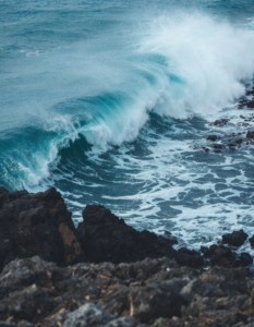 A powerful wave crashing against a rocky coastline, showcasing the raw power and energy of the ocean