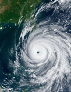 A satellite view of a hurricane swirling over the ocean, its eye clearly visible amidst the powerful storm clouds